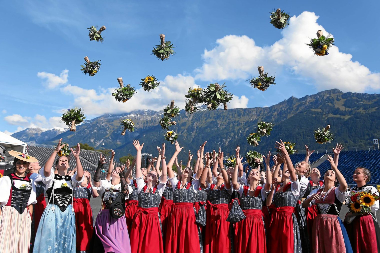 Die in Tracht gekleideten Ehrendamen des Unspunnenfests werfen Blumensträusse in die Höhe. 